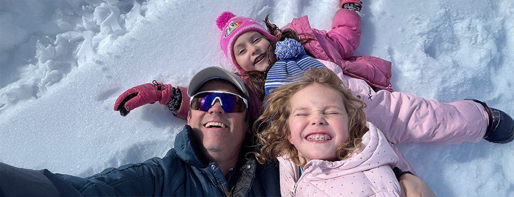 Image of Justin Osmond and two daughters laying in the snow